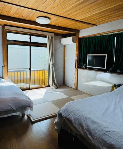 a bedroom with a bed and a tv on the wall at 日久の宿 in Kokubunji