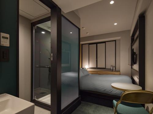 a bedroom with a bed and a table and a glass door at BASE LAYER HOTEL Nagoya Nishiki in Nagoya