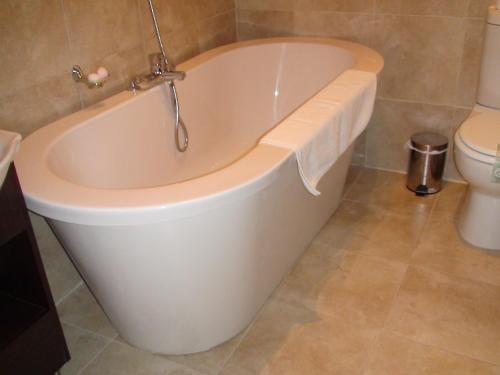 a white bath tub in a bathroom with a toilet at Villa Lugano Guesthouse in Johannesburg