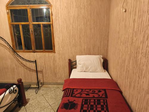 a small bedroom with a bed and a window at Hotel El Golla in Er Rachidia