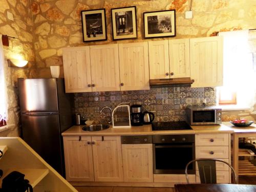 a kitchen with wooden cabinets and a stainless steel refrigerator at Alegria Villas Complex in Vasilikos