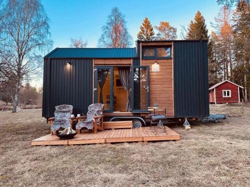 a tiny house with a deck and two chairs at Stockholm Archipelago by Tiny Away in Fagerdala