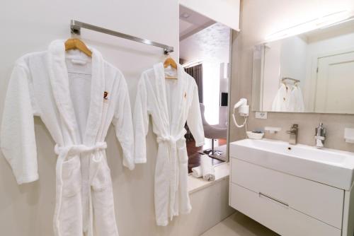 a bathroom with white robes hanging on a wall at Rafaelo Deluxe Hotel & Spa Shengjin in Shëngjin
