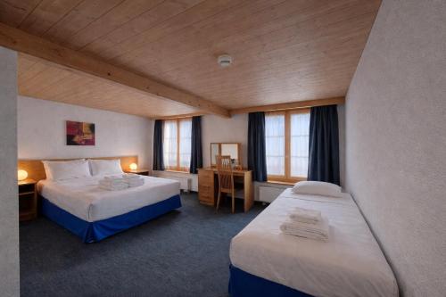 ein Hotelzimmer mit zwei Betten und zwei Fenstern in der Unterkunft Chalet Rosa B&B in Lauterbrunnen
