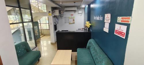 a waiting room with two green chairs and a counter at Open Hotel by Olive - Sadha Siva Airport Road, Chennai in Chennai