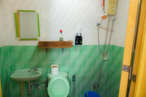 a green and white bathroom with a sink and a toilet at Puerto Galera Transient Kubo Guest Place in Puerto Galera