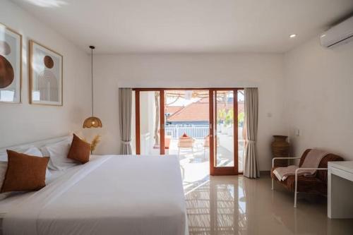 a bedroom with a white bed and a sliding glass door at Villa OG Cruz in Canggu