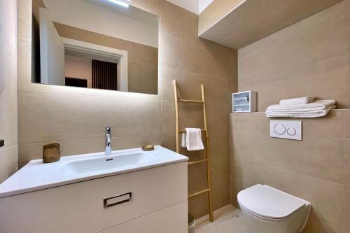 a bathroom with a sink and a toilet and a mirror at Villas Punta Silo - luxury apartments with pool in Šilo