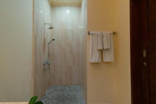 a bathroom with a shower with white towels at Umah Gatra Ubud in Ubud