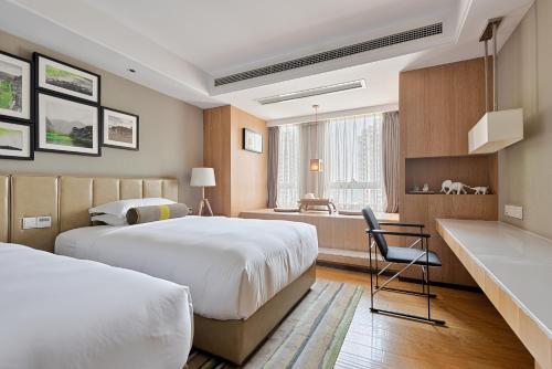 a hotel room with two beds and a desk at 两江万励OneJasper空中江景酒店 in Chongqing