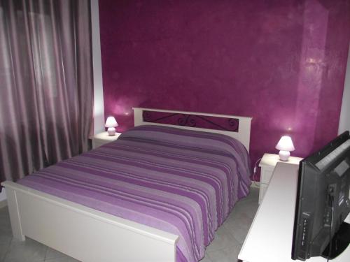 a purple bedroom with a bed with purple walls at Il Glicine in Capo dʼOrlando