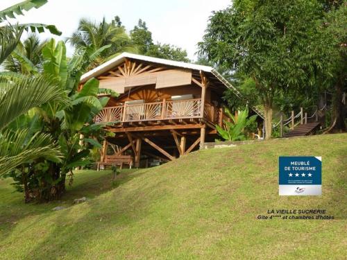 a house on a hill with a sign in front of it at Gîte 4 étoiles, la Vieille Sucrerie St Claude Guadeloupe, Jacuzzi Spa privatif, vue exceptionnelle sur la mer des Caraïbes in Basse-Terre