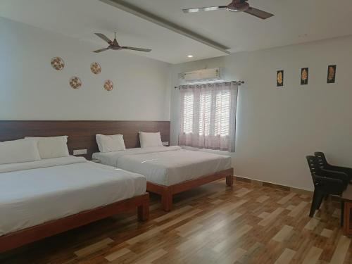 a bedroom with two beds and a ceiling fan at Dayanand Residency in Chitradurga