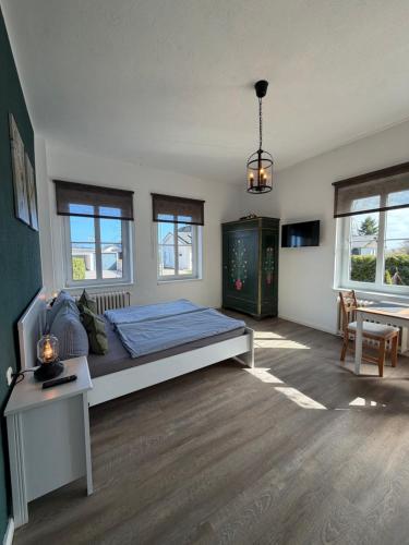 a bedroom with a bed and a table and windows at Gästehaus Kleiner Wacholder in Bad Doberan