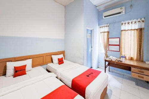 two beds in a room with blue walls and red pillows at RedDoorz at Arca Hostel Lampung in Lampung