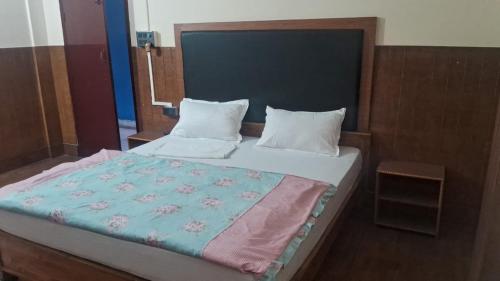a bedroom with a large bed with a blue blanket at Hotel Silver Dragon, NK Darranga in Darranga
