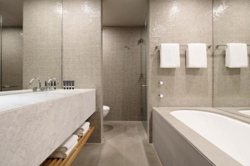 a bathroom with a sink, toilet and bathtub at Hotel Realm in Canberra