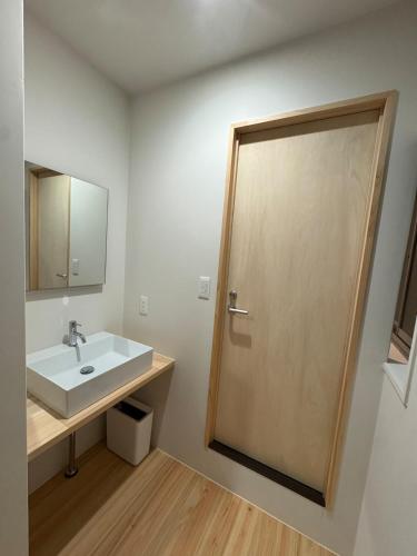 a bathroom with a sink and a wooden door at 5名様まで宿泊可能 四万十市下田の一棟貸し宿 明の宿 akari in Shimanto