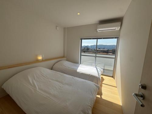 two beds in a small room with a window at 5名様まで宿泊可能 四万十市下田の一棟貸し宿 明の宿 akari in Shimanto