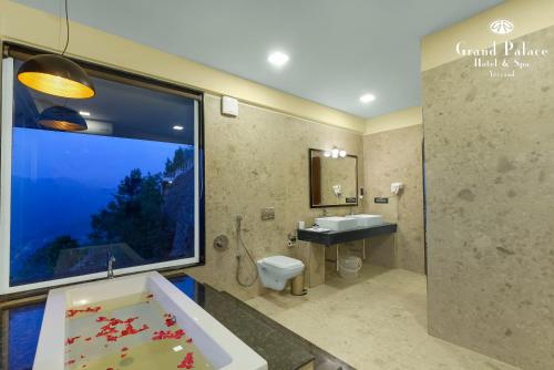 a bathroom with a tub and a sink and a window at Grand Palace Hotel & Spa in Yercaud