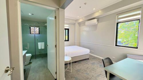 a bedroom with a bed and a table and a bathroom at The Ancestry Suites in Wasig
