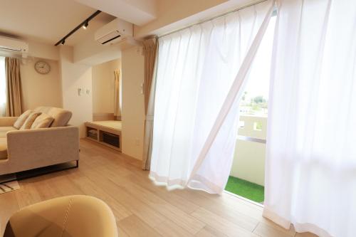a living room with a couch and a large window at muniyuitsu 宮古島 spa&park in Miyako-jima