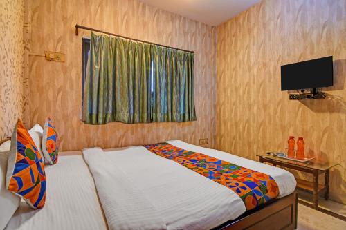 a bedroom with a bed and a tv on the wall at FabHotel Step Inn Stays in Ballygunge