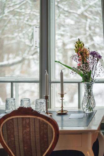a table with a vase of flowers and candles on a window at Kansjerf Gård in Bromary