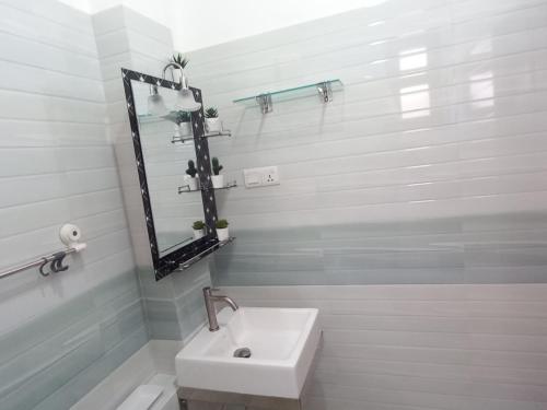 a white bathroom with a sink and a mirror at Villa 86 in Pamunugama