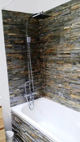 a bathroom with a bath tub with a stone wall at Chambre double 30km de la Tour Eiffel in Saint-Michel-sur-Orge