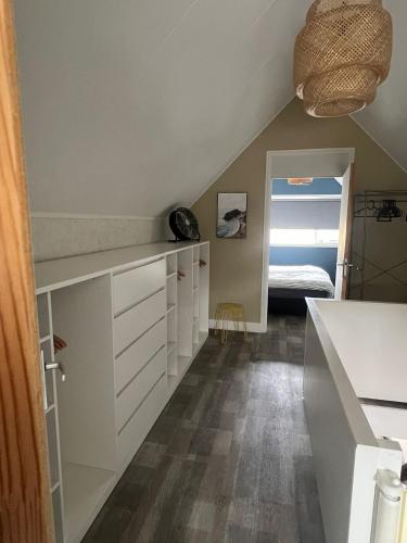 a kitchen with white cabinets and a bed in a room at Een heerlijke vakantiewoning aan de Zeeuwse kust in Breskens