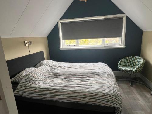 a bedroom with a bed and a window and a chair at Een heerlijke vakantiewoning aan de Zeeuwse kust in Breskens