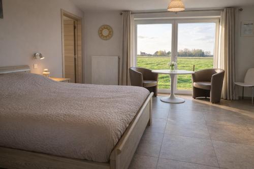 a bedroom with a bed and a table with chairs at B&B Het Polderhof in Jabbeke