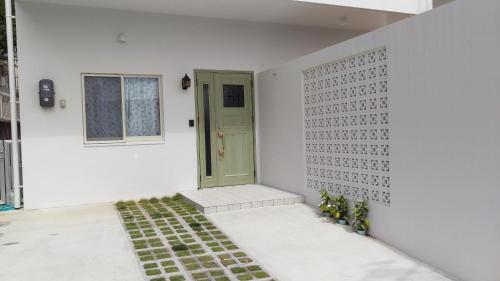 浦添市にあるＧＲＥＥＮ　ＨＯＵＳＥの緑のドアと植物のある白い部屋