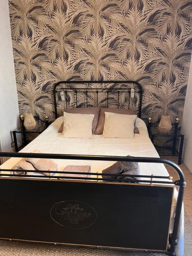un letto con struttura nera e una parete di Les Fleurs a Monpazier