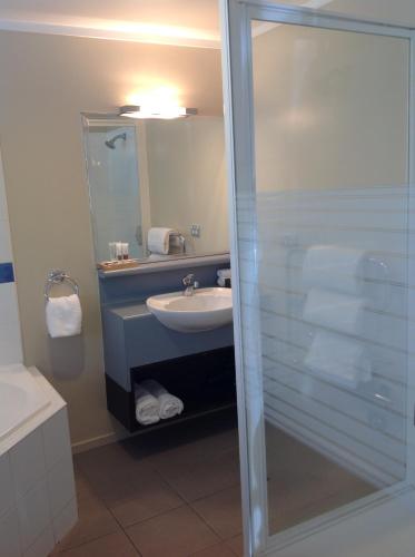 a bathroom with a shower and a sink and a mirror at Sails on the Lake in Taupo