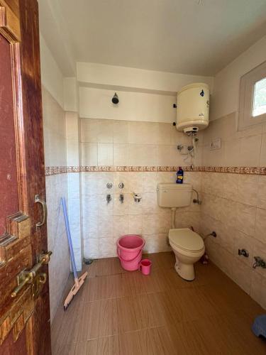 a bathroom with a toilet and a pink bucket at Walking Trails homestay in Baragrān