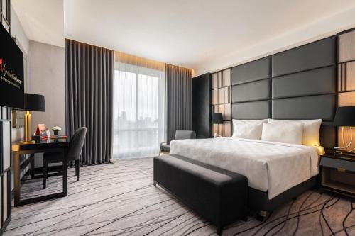 a hotel room with a bed and a desk at Grand Swiss-Belhotel Darmo in Surabaya