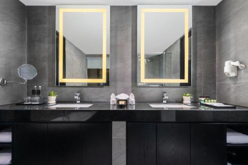 a bathroom with two sinks and two mirrors at Grand Swiss-Belhotel Darmo in Surabaya