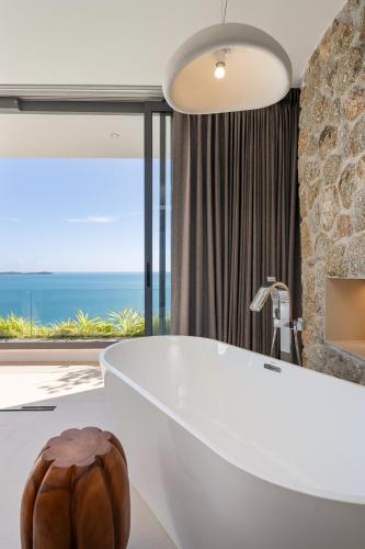 a bathroom with a tub with a view of the ocean at Sukkho Samui Estates in Chaweng Noi Beach