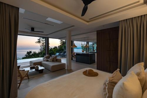 a bedroom with a large bed and a living room at Sukkho Samui Estates in Chaweng Noi Beach