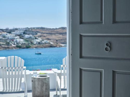 eine Tür mit weißen Stühlen und Blick aufs Wasser in der Unterkunft Pietra e Mare - Mykonos Moments by Mr and Mrs White in Kalo Livadi