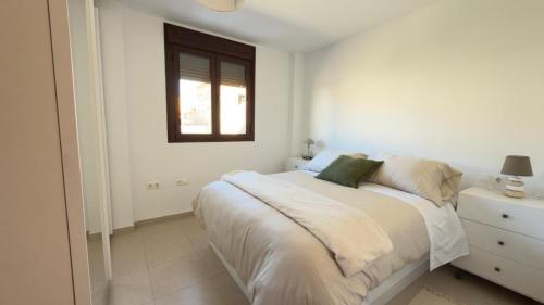 a white bedroom with a bed and a window at Casa Xandra in Tabernas