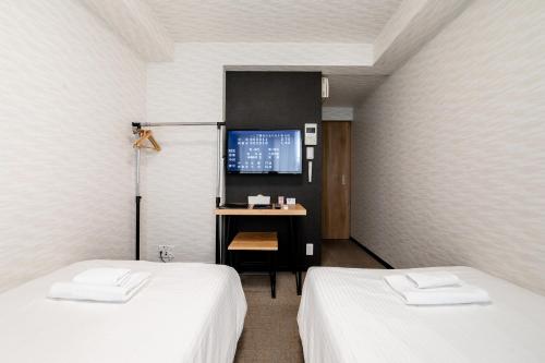 a room with two beds and a desk with a monitor at New open! Hopetree 京都 in Kyoto