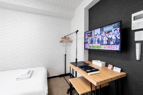 a bedroom with a bed and a tv on a wall at New open! Hopetree 京都 in Kyoto