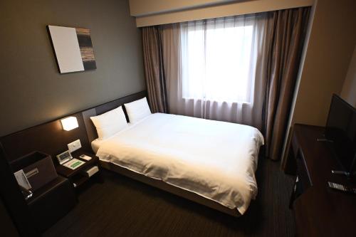 a hotel room with a bed and a window at Dormy Inn Hakata Gion in Fukuoka