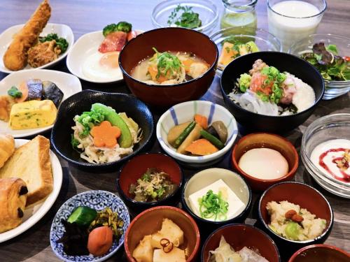 a table topped with bowls of different types of food at Dormy Inn Hakata Gion in Fukuoka