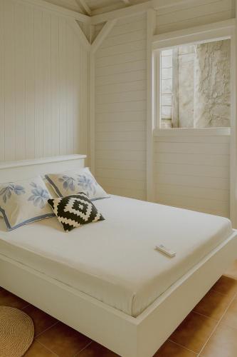 a white bed with two pillows and a window at Séjour Caraïbe in Pointe-Noire