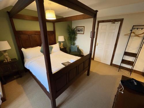 a bedroom with a large wooden canopy bed with white sheets at True Lovers Knot, Tarrant Keyneston in Tarrant Keynston