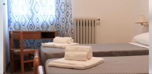 a bedroom with two beds and a desk and a chair at Moderno Albergo Didattico in San Pellegrino Terme